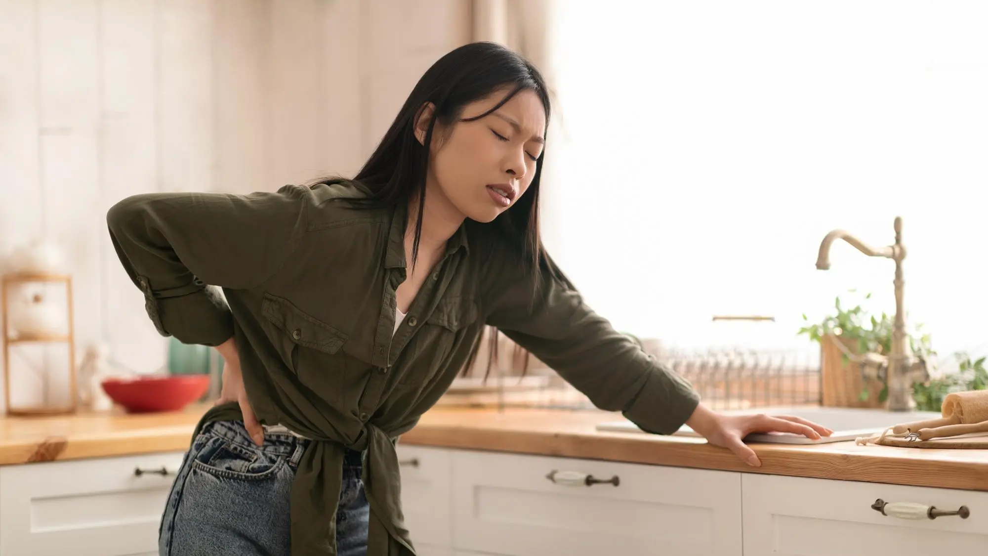 Douleur aiguë ou douleur chronique : comment comprendre ce que votre corps vous dit Femme souffrant de douleur lombaire aiguë en se tenant le bas du dos à la maison